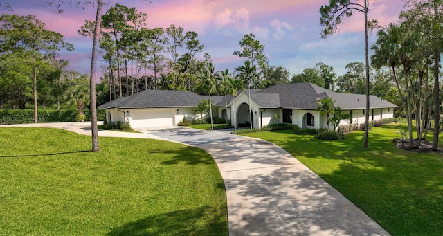 view of front of property featuring concrete driveway, a yard, and a garage