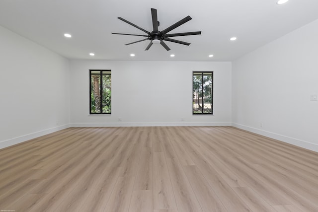 empty room with recessed lighting, plenty of natural light, light wood finished floors, and baseboards