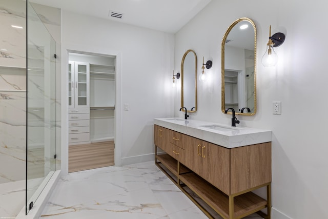 full bathroom featuring baseboards, a marble finish shower, marble finish floors, a spacious closet, and double vanity
