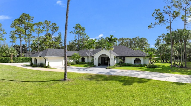ranch-style home featuring driveway, a front yard, a garage, and stucco siding