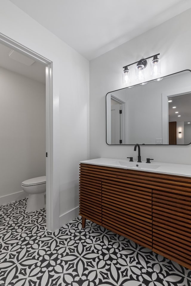 bathroom featuring baseboards, toilet, and vanity