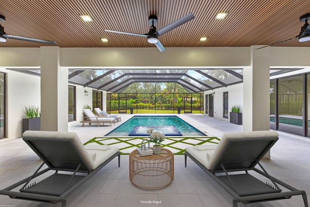 swimming pool with ceiling fan, a patio, and glass enclosure
