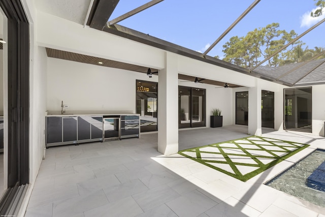 view of patio / terrace with a ceiling fan, glass enclosure, and a sink