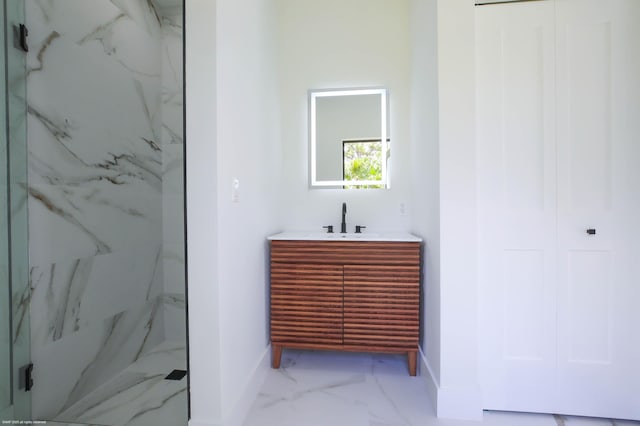 full bath with marble look tiles, a marble finish shower, baseboards, and vanity