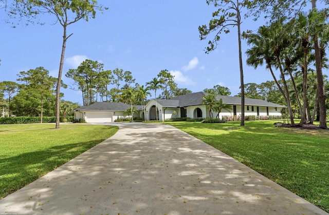 ranch-style home featuring a front lawn, an attached garage, and driveway