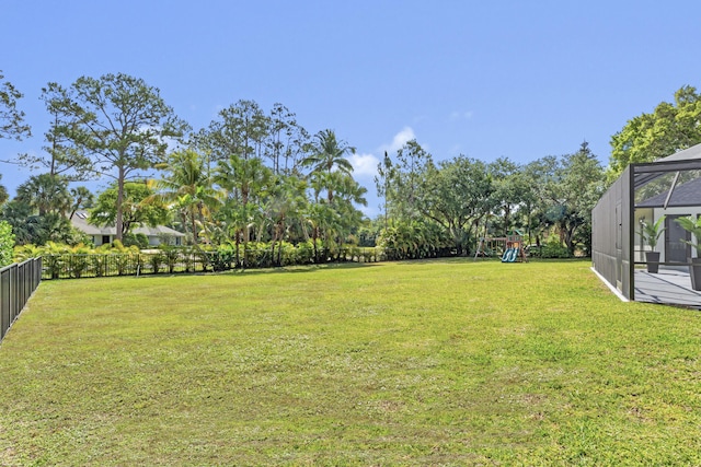 view of yard featuring a playground and glass enclosure