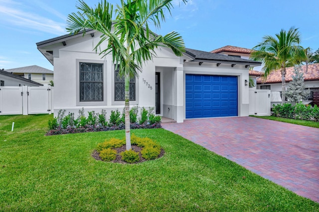 view of front facade with an attached garage, a gate, stucco siding, and decorative driveway