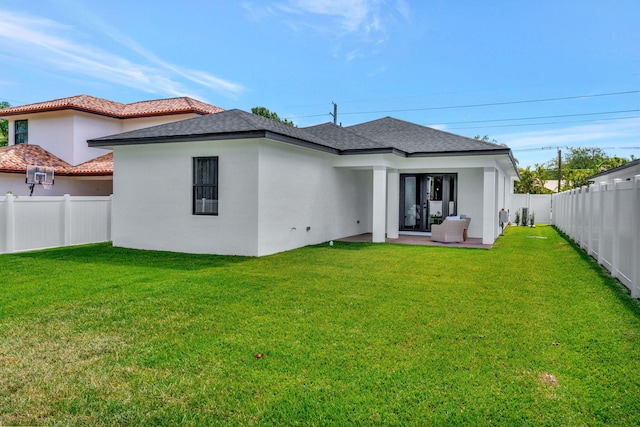back of house with a fenced backyard, a patio, stucco siding, and a yard