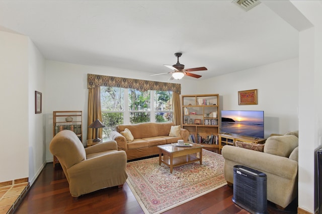 living room with a ceiling fan, visible vents, and dark wood-style floors