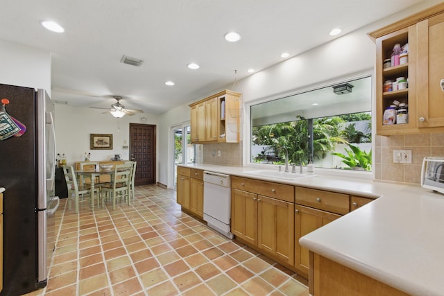 kitchen with a sink, freestanding refrigerator, visible vents, backsplash, and white dishwasher