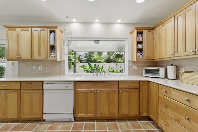 kitchen with white dishwasher, a toaster, a sink, open shelves, and light countertops