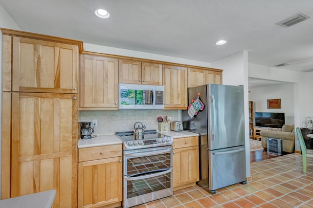 kitchen featuring light brown cabinetry, visible vents, backsplash, light countertops, and appliances with stainless steel finishes
