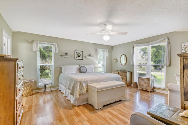 bedroom with light wood finished floors, baseboards, and ceiling fan