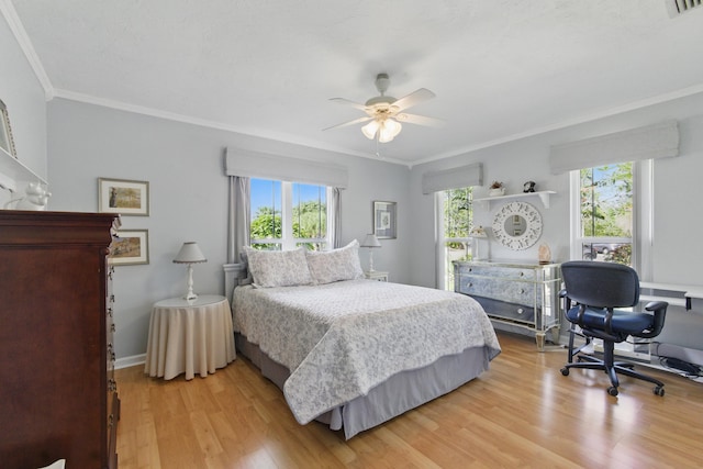 bedroom featuring light wood finished floors, visible vents, baseboards, ceiling fan, and ornamental molding