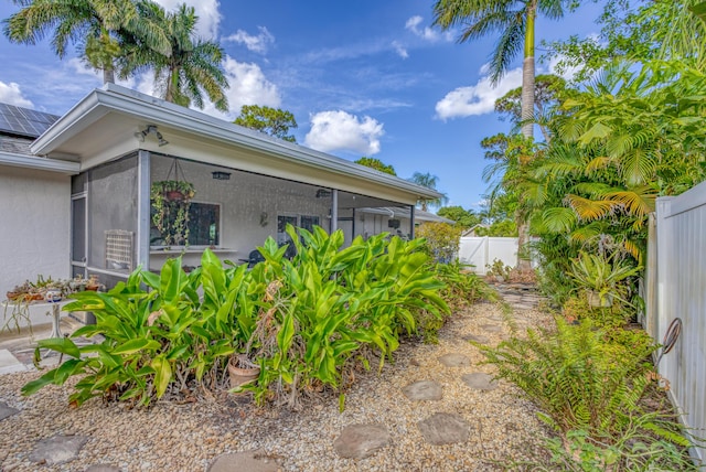 view of side of home featuring a sunroom, stucco siding, and fence