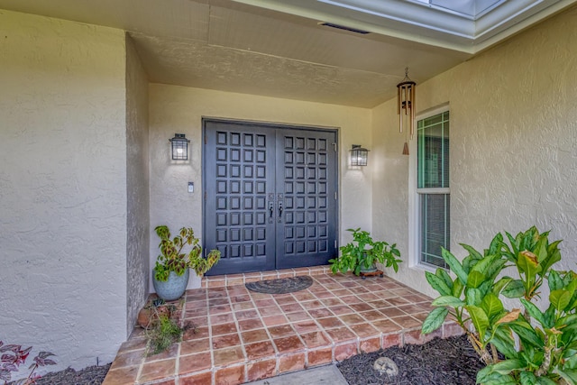 view of exterior entry with stucco siding and visible vents