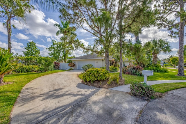 view of front of property featuring fence, an attached garage, concrete driveway, a front yard, and a gate