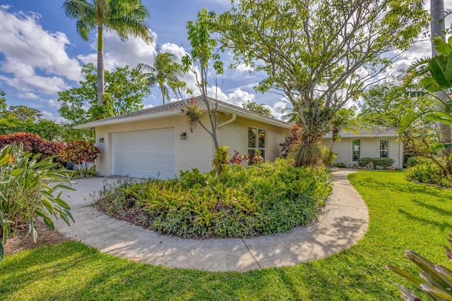 view of side of home with a yard, an attached garage, stucco siding, and driveway
