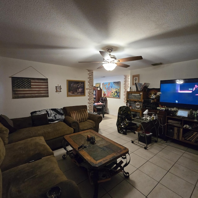 living room with light tile patterned floors, a ceiling fan, a textured ceiling, and visible vents