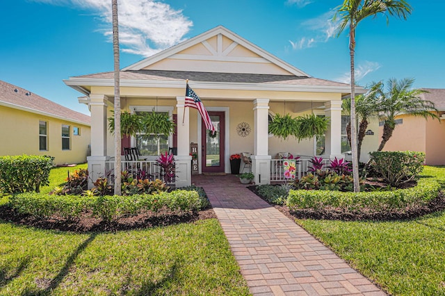 10327 SW W Park Ave, Port Saint Lucie, FL 34987 - view of front facade featuring covered porch, stucco siding, a shingled roof, and a front lawn