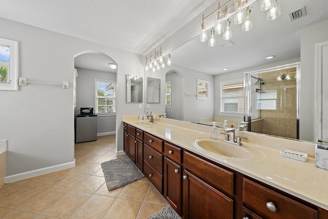 5769 SE Crooked Oak Ave, Hobe Sound, FL 33455 - bathroom with tile patterned flooring, a stall shower, double vanity, a textured ceiling, and baseboards