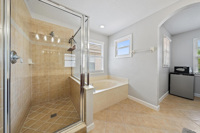 5769 SE Crooked Oak Ave, Hobe Sound, FL 33455 - full bathroom with tile patterned flooring, a shower stall, a garden tub, baseboards, and a textured ceiling