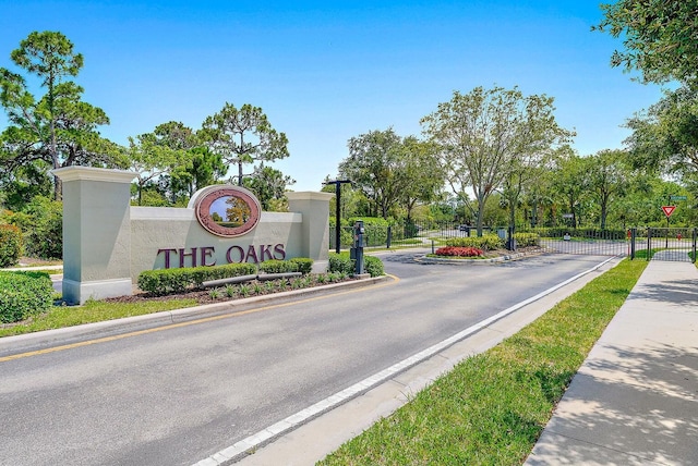 view of street featuring sidewalks, a gated entry, curbs, a gate, and street lights
