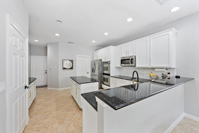 5769 SE Crooked Oak Ave, Hobe Sound, FL 33455 - kitchen with appliances with stainless steel finishes, dark stone counters, white cabinetry, recessed lighting, and baseboards