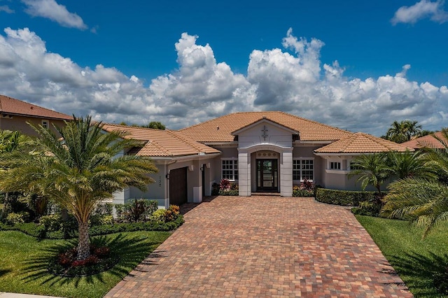 132 Steeple Cir, Jupiter, FL 33458 - mediterranean / spanish-style house with decorative driveway, a garage, a tiled roof, stucco siding, and a front lawn