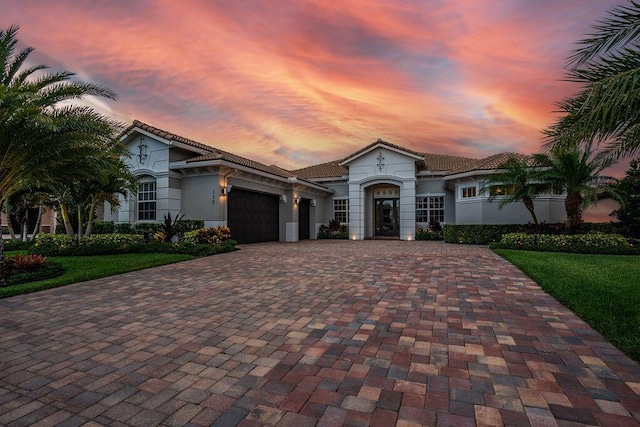 132 Steeple Cir, Jupiter, FL 33458 - mediterranean / spanish house with decorative driveway, an attached garage, a tiled roof, stucco siding, and a yard