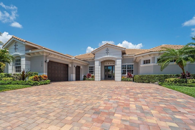 132 Steeple Cir, Jupiter, FL 33458 - mediterranean / spanish house with an attached garage, a tile roof, stucco siding, and decorative driveway