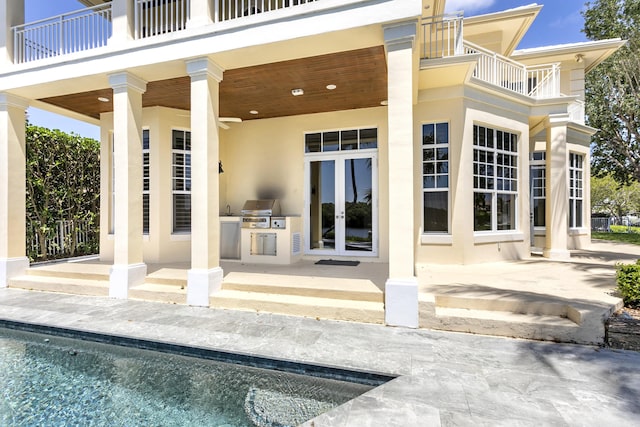 back of house with a balcony, french doors, a patio, and an outdoor pool
