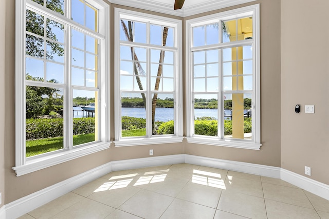 unfurnished dining area featuring tile patterned floors, baseboards, a water view, and a ceiling fan