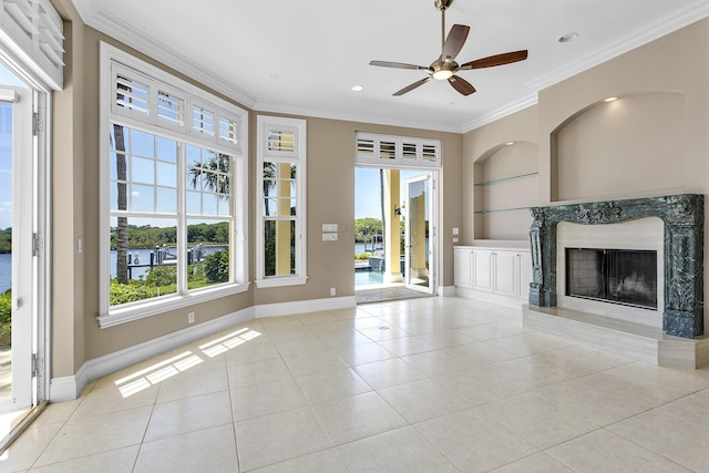 unfurnished living room with built in features, ceiling fan, light tile patterned floors, a premium fireplace, and a water view