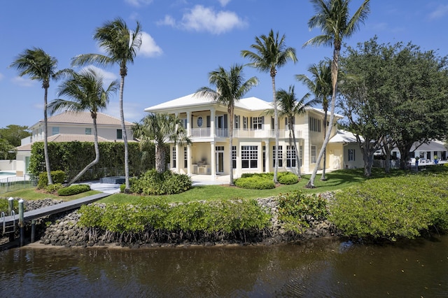 rear view of property featuring a balcony, a water view, and stucco siding