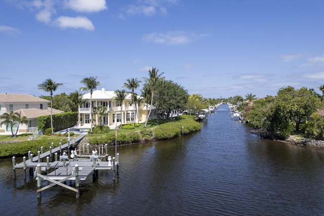 dock with boat lift, a water view, and a balcony