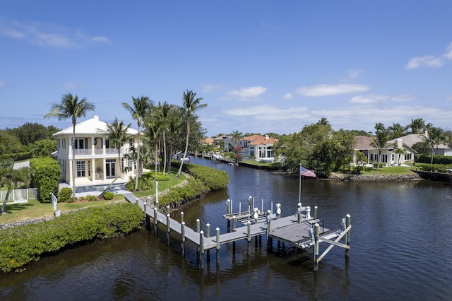 dock with boat lift, a balcony, a water view, fence, and a residential view