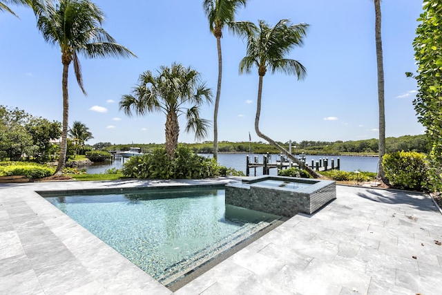 outdoor pool with an in-ground hot tub, a water view, and a patio area