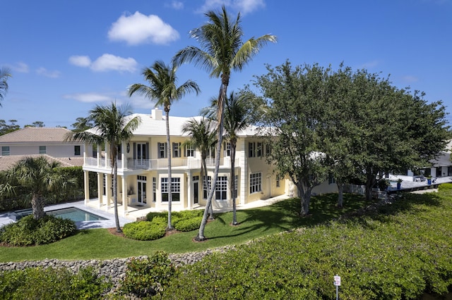 rear view of property with a balcony, a yard, a patio area, and an outdoor pool