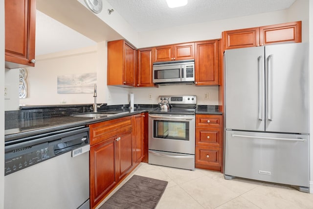 7240 Huntington Ln Unit 105, Delray Beach, FL 33446 - kitchen with light tile patterned floors, a sink, dark stone counters, brown cabinetry, and appliances with stainless steel finishes