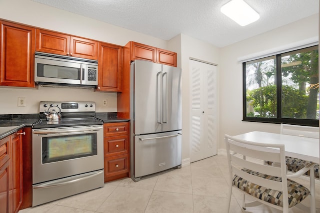 7240 Huntington Ln Unit 105, Delray Beach, FL 33446 - kitchen featuring a textured ceiling, dark countertops, light tile patterned floors, and appliances with stainless steel finishes