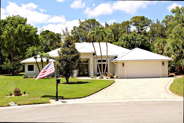view of front of property featuring driveway, french doors, a garage, a front lawn, and stucco siding