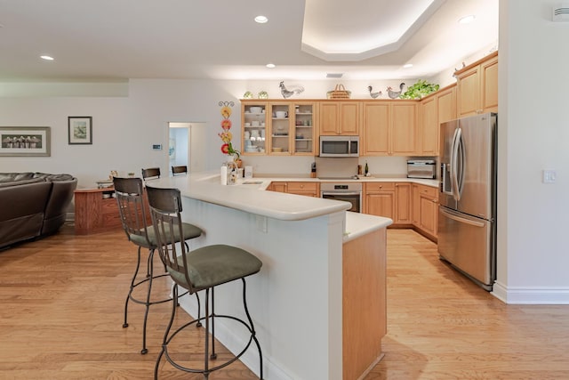 8005 SW Yachtsmans Dr, Stuart, FL 34997 - kitchen featuring stainless steel appliances, a breakfast bar area, a peninsula, light brown cabinetry, and light wood-style floors