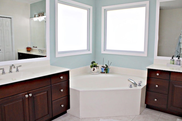 bathroom featuring a bath, two vanities, and tile patterned floors