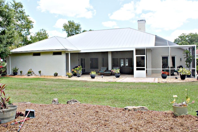 rear view of house with a chimney, a lawn, and stucco siding
