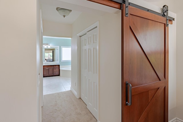 8005 SW Yachtsmans Dr, Stuart, FL 34997 - corridor featuring light colored carpet, a barn door, light tile patterned floors, and baseboards