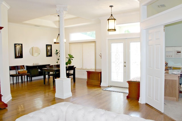 entrance foyer with light wood-type flooring, plenty of natural light, a tray ceiling, decorative columns, and ornamental molding