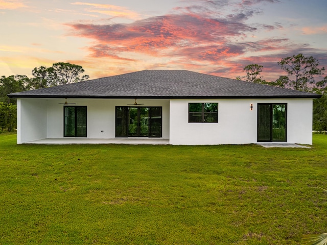 17816 86th St N, The Acreage, FL 33470 - back of house at dusk with a patio, a ceiling fan, roof with shingles, and stucco siding