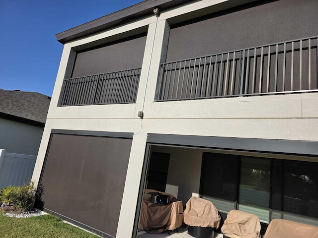 exterior space featuring fence, a balcony, and stucco siding
