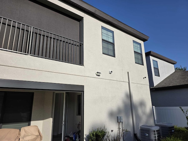 view of side of property with central AC unit and stucco siding